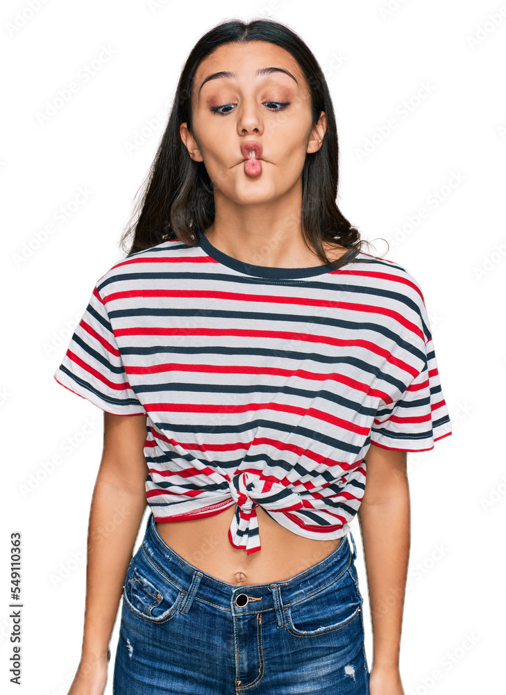 Fototapeta premium Young hispanic girl wearing casual clothes making fish face with lips, crazy and comical gesture. funny expression.