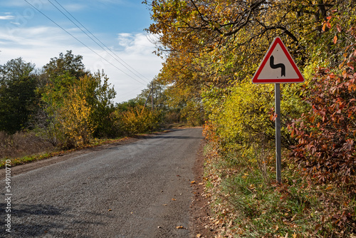 The sign warns of a sharp turn in the road. Nature of the countryside in Ukraine