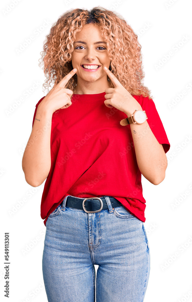 Young blonde woman with curly hair wearing casual red tshirt smiling cheerful showing and pointing with fingers teeth and mouth. dental health concept. Young blonde woman with curly hair wearing casual red tshirt smiling cheerful showing and pointing with fingers teeth and mouth. dental health concept.