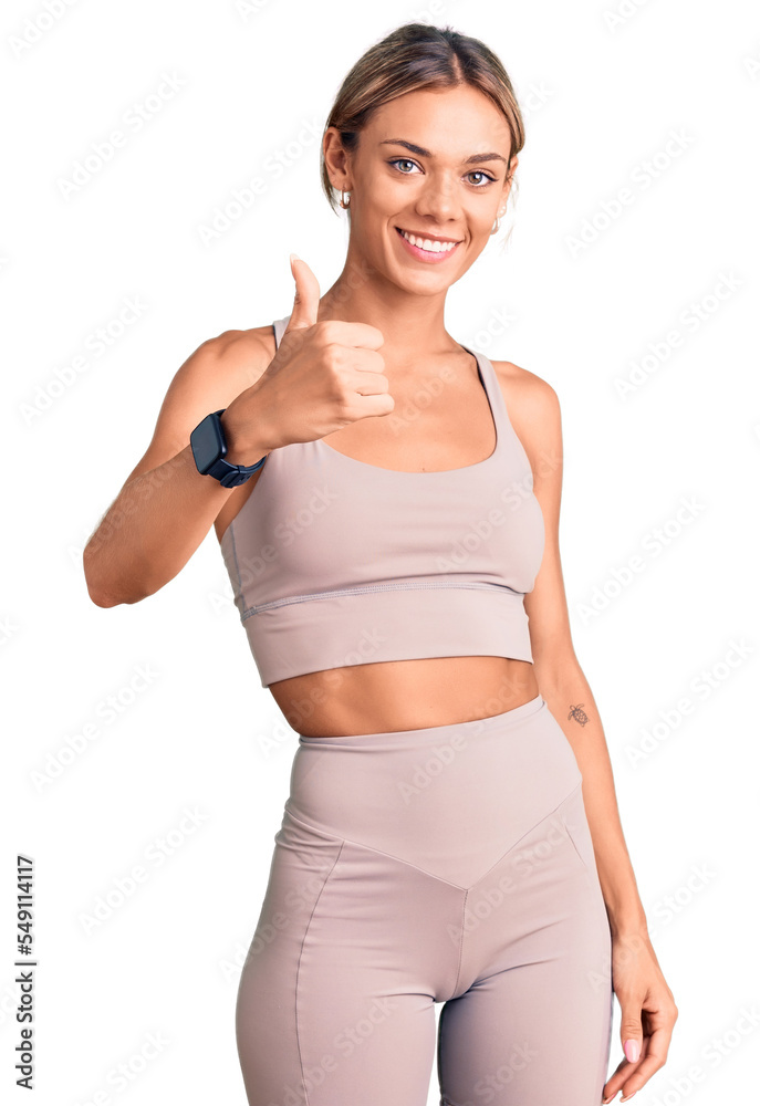 Beautiful caucasian woman wearing sportswear doing happy thumbs up gesture with hand. approving expression looking at the camera showing success. Beautiful caucasian woman wearing sportswear doing happy thumbs up gesture with hand. approving expression looking at the camera showing success.