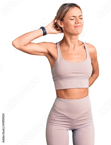 Beautiful caucasian woman wearing sportswear suffering of neck ache injury, touching neck with hand, muscular pain