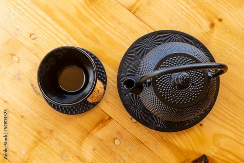 Top view of a cast iron teapot and a tea cup, mug set on a wooden table