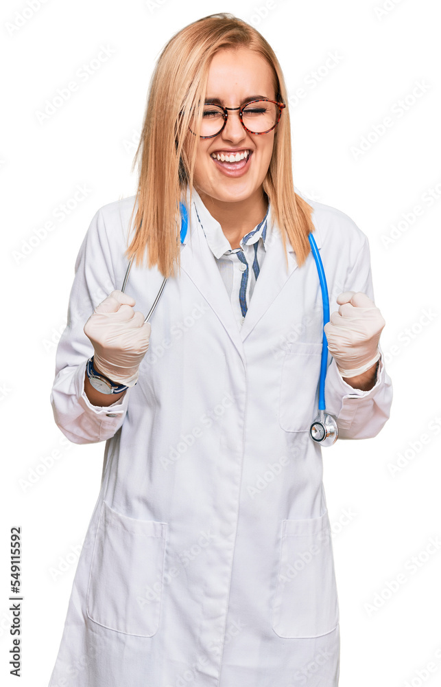 Beautiful caucasian woman wearing doctor uniform and stethoscope very happy and excited doing winner gesture with arms raised, smiling and screaming for success. celebration concept.