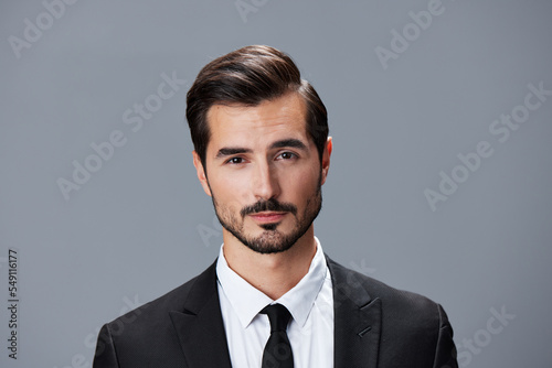 Portrait of a business man in a stylish suit with tie beautiful face on a gray isolated background. Business concept young businessman startup copy space