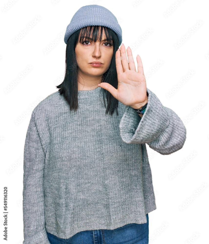 Young hispanic woman wearing cute wool cap doing stop sing with palm of the hand. warning expression with negative and serious gesture on the face. Young hispanic woman wearing cute wool cap doing stop sing with palm of the hand. warning expression with negative and serious gesture on the face.
