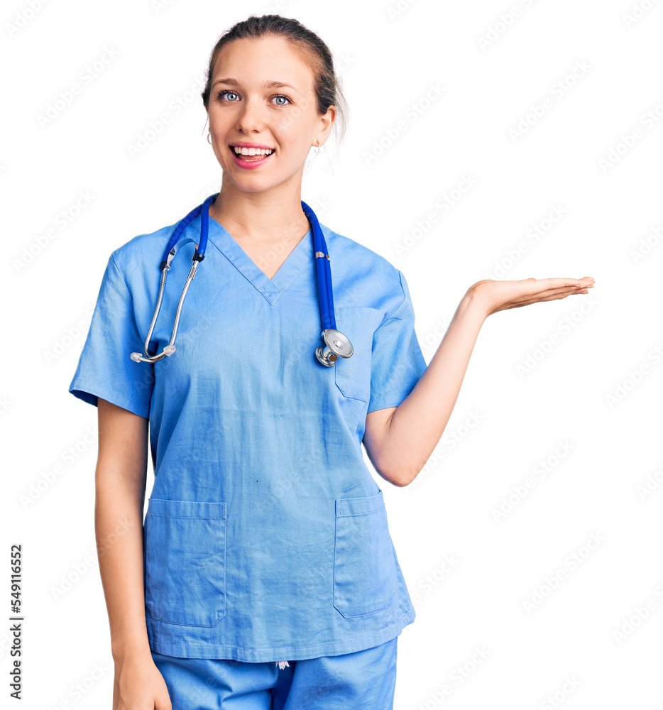 Young beautiful blonde woman wearing doctor uniform and stethoscope smiling cheerful presenting and pointing with palm of hand looking at the camera. Young beautiful blonde woman wearing doctor uniform and stethoscope smiling cheerful presenting and pointing with palm of hand looking at the camera.