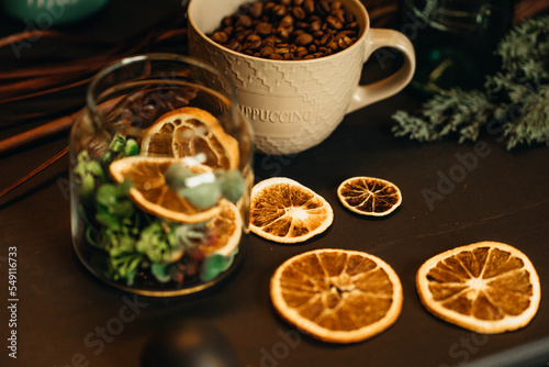 cup with coffee beans on the table with dry oranges