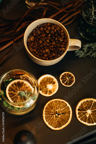 cup with coffee beans on the table with dry oranges