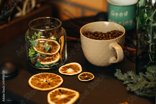 cup with coffee beans on the table with dry oranges
