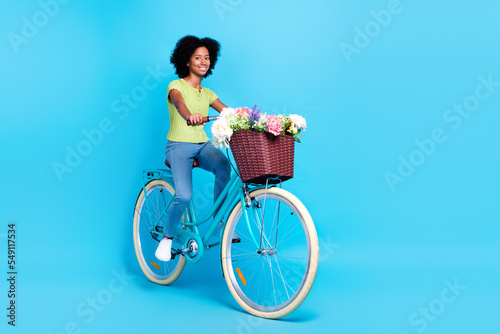 Full length size photo of little funny active positive schoolgirl teenager riding her retro bicycle busket flowers chilling isolated on blue color background