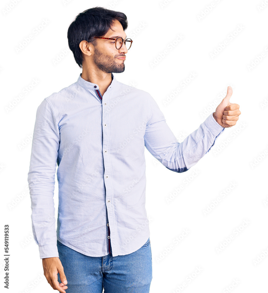 Handsome hispanic man wearing business shirt and glasses looking proud, smiling doing thumbs up gesture to the side Handsome hispanic man wearing business shirt and glasses looking proud, smiling doing thumbs up gesture to the side