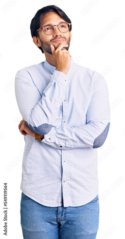Handsome hispanic man wearing business shirt and glasses with hand on chin thinking about question, pensive expression. smiling with thoughtful face. doubt concept. Handsome hispanic man wearing business shirt and glasses with hand on chin thinking about question, pensive expression. smiling with thoughtful face. doubt concept.