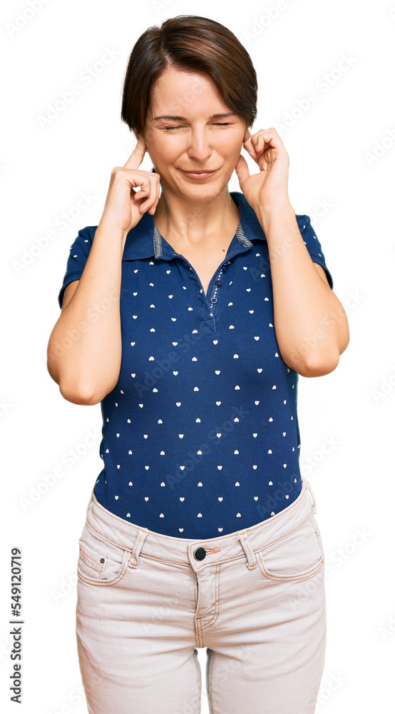Young brunette woman with short hair wearing casual clothes covering ears with fingers with annoyed expression for the noise of loud music. deaf concept. Young brunette woman with short hair wearing casual clothes covering ears with fingers with annoyed expression for the noise of loud music. deaf concept.