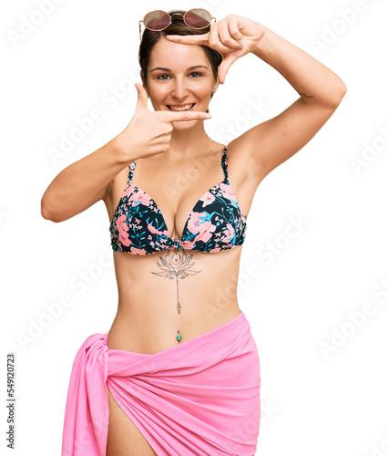 Young brunette woman with short hair wearing bikini smiling making frame with hands and fingers with happy face. creativity and photography concept.