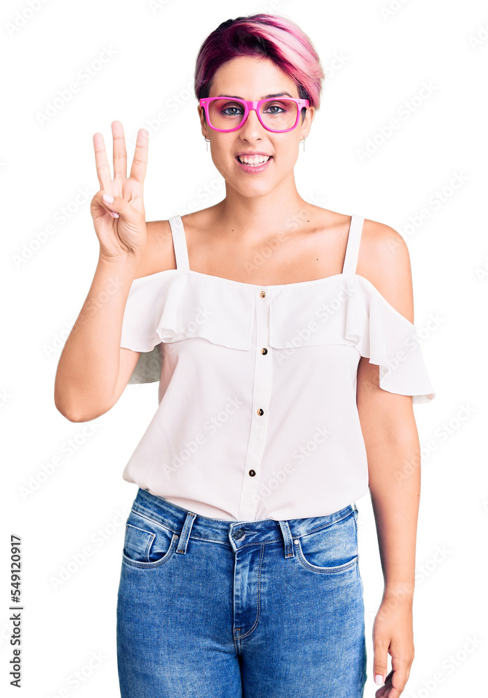 Young beautiful woman with pink hair wearing casual clothes and glasses showing and pointing up with fingers number three while smiling confident and happy. Young beautiful woman with pink hair wearing casual clothes and glasses showing and pointing up with fingers number three while smiling confident and happy.