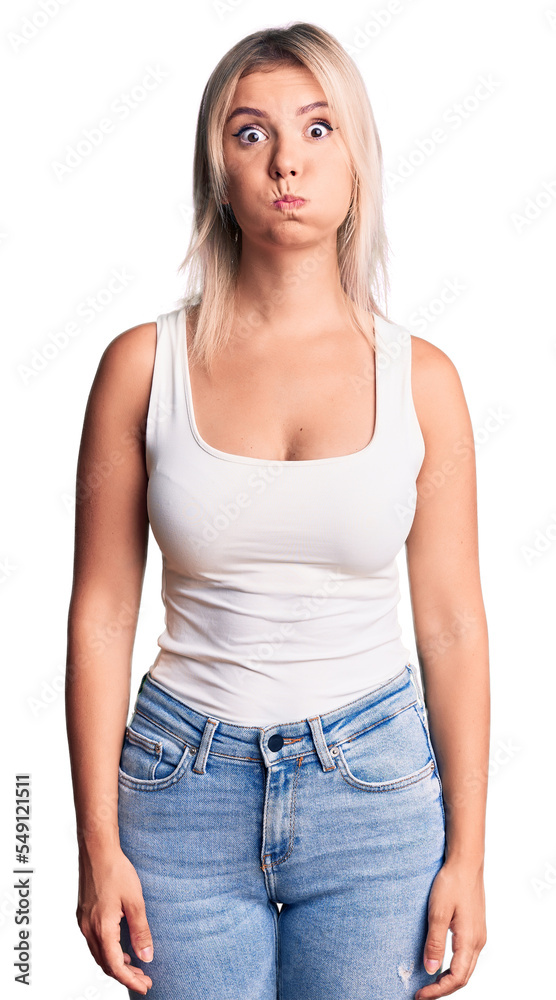 Young beautiful blonde woman wearing casual sleeveless t-shirt puffing cheeks with funny face. mouth inflated with air, crazy expression. Young beautiful blonde woman wearing casual sleeveless t-shirt puffing cheeks with funny face. mouth inflated with air, crazy expression.