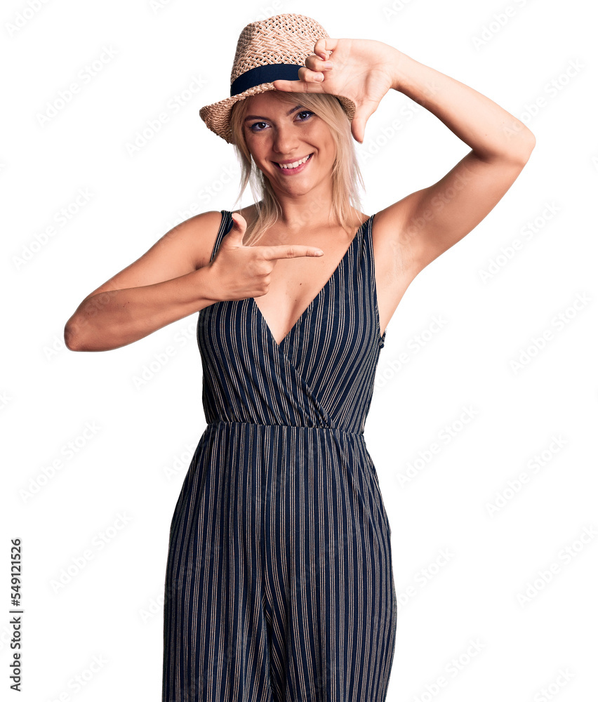 Young beautiful blonde woman wearing summer hat and dress smiling making frame with hands and fingers with happy face. creativity and photography concept. Young beautiful blonde woman wearing summer hat and dress smiling making frame with hands and fingers with happy face. creativity and photography concept.