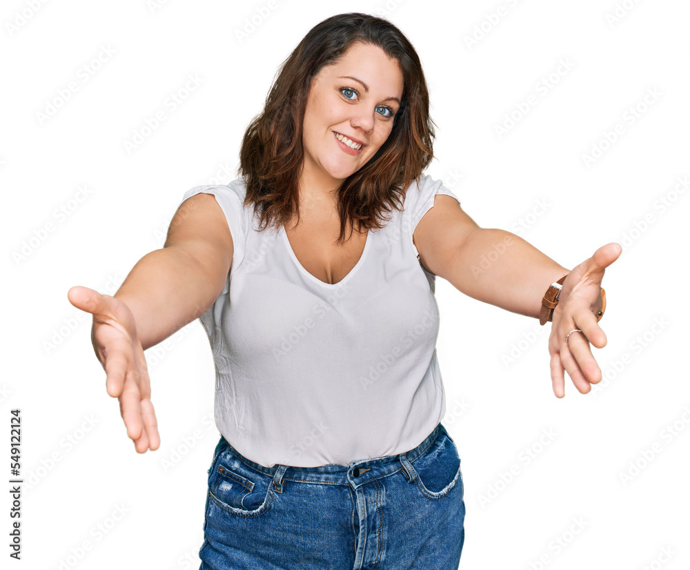 Young plus size woman wearing casual white t shirt looking at the camera smiling with open arms for hug. cheerful expression embracing happiness. Young plus size woman wearing casual white t shirt looking at the camera smiling with open arms for hug. cheerful expression embracing happiness.