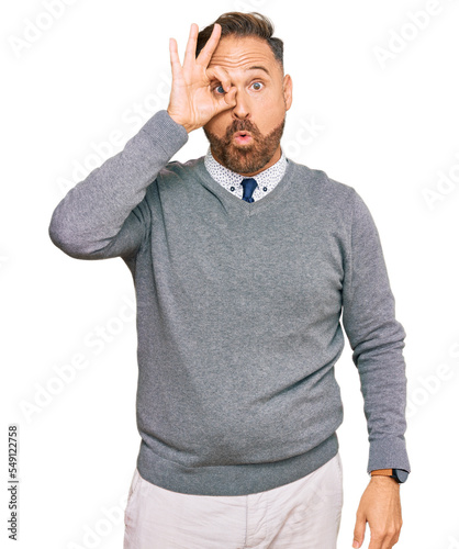 Vászonkép Handsome middle age man wearing business clothes doing ok gesture shocked with surprised face, eye looking through fingers