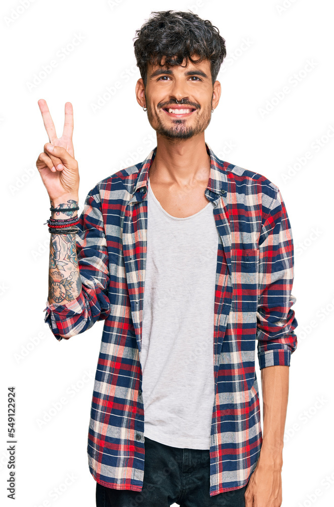 Young hispanic man wearing casual clothes showing and pointing up with fingers number two while smiling confident and happy. Young hispanic man wearing casual clothes showing and pointing up with fingers number two while smiling confident and happy.