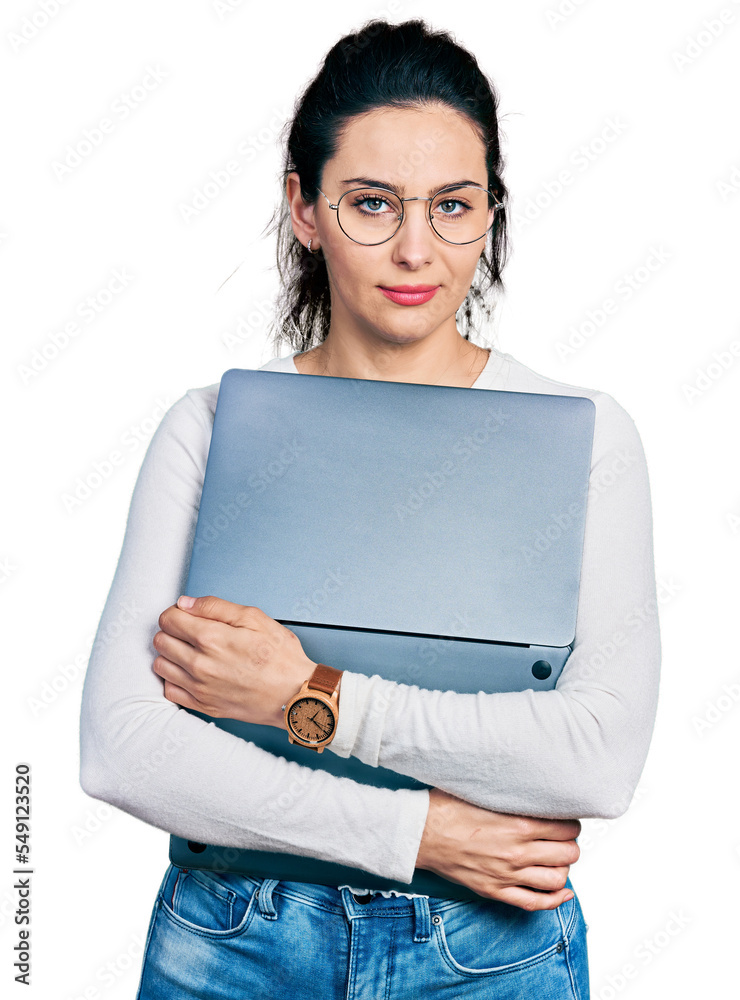 Young hispanic woman working using computer laptop relaxed with serious expression on face. simple and natural looking at the camera. Young hispanic woman working using computer laptop relaxed with serious expression on face. simple and natural looking at the camera.