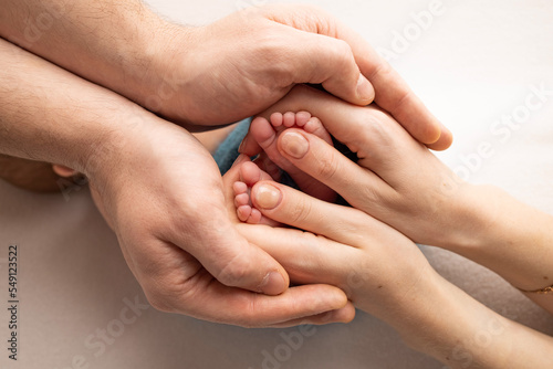 Mother is doing massage on her baby foot. Close up baby feet in mother hands on a white background. Prevention of flat feet, development, muscle tone, dysplasia. Family, love, care, and health concept