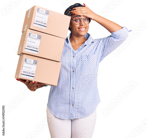 Young african american woman with braids holding delivery packages stressed and frustrated with hand on head, surprised and angry face photo