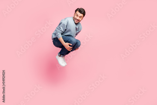 Full size photo of handsome young man jumping high bomb swimming pool copyspace wear stylish blue outfit isolated on pink color background