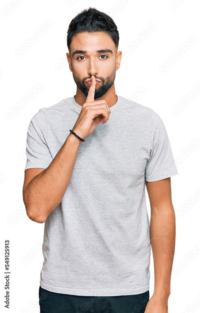 Young man with beard wearing casual grey tshirt asking to be quiet with finger on lips. silence and secret concept. Young man with beard wearing casual grey tshirt asking to be quiet with finger on lips. silence and secret concept.
