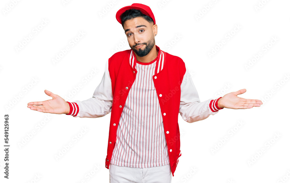 Young man with beard wearing baseball uniform clueless and confused expression with arms and hands raised. doubt concept. Young man with beard wearing baseball uniform clueless and confused expression with arms and hands raised. doubt concept.