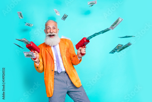 Photo of cheerful eccentric man trendy orange costume shooting paper usd cool luxury life empty space isolated on cyan color background