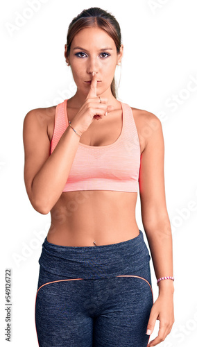 Young beautiful hispanic woman wearing sportswear asking to be quiet with finger on lips. silence and secret concept.