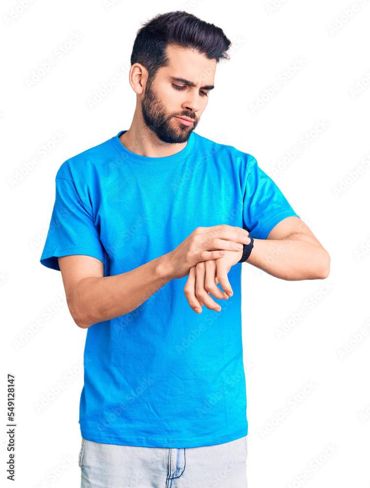 Young handsome man with beard wearing casual t-shirt checking the time on wrist watch, relaxed and confident Young handsome man with beard wearing casual t-shirt checking the time on wrist watch, relaxed and confident