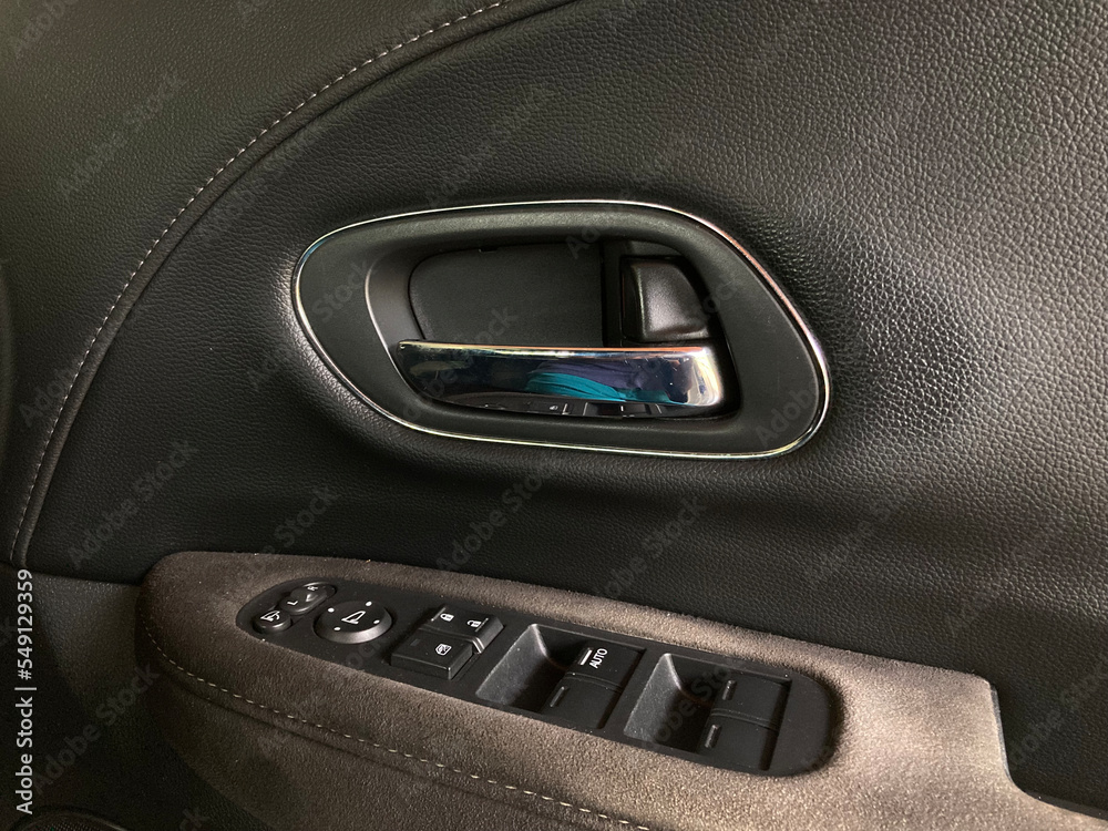 chrome car door handle with leather and Alcantara lining around plastic buttons