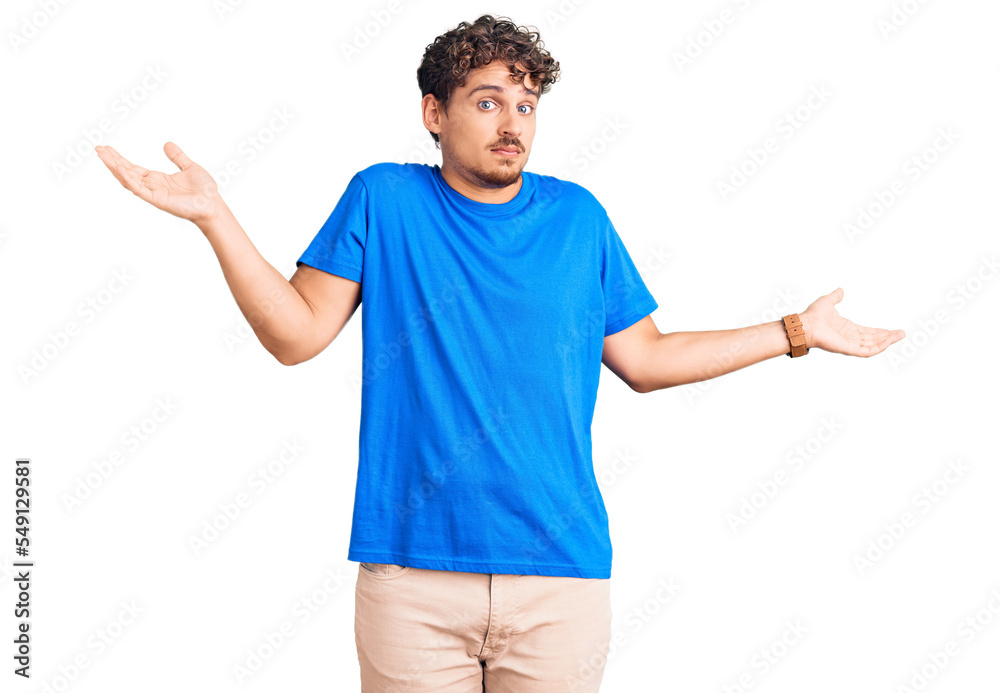 Young handsome man with curly hair wearing casual clothes clueless and confused expression with arms and hands raised. doubt concept. Young handsome man with curly hair wearing casual clothes clueless and confused expression with arms and hands raised. doubt concept.