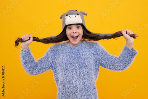 Modern teen girl wearing sweater and knitted hat on isolated yellow background. Surprised teenager girl.