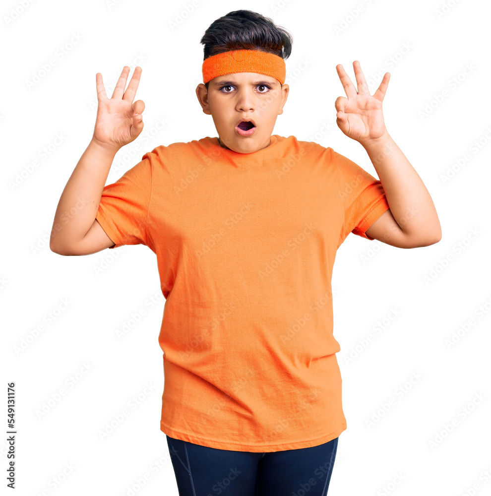 Little boy kid wearing sportswear looking surprised and shocked doing ok approval symbol with fingers. crazy expression Little boy kid wearing sportswear looking surprised and shocked doing ok approval symbol with fingers. crazy expression