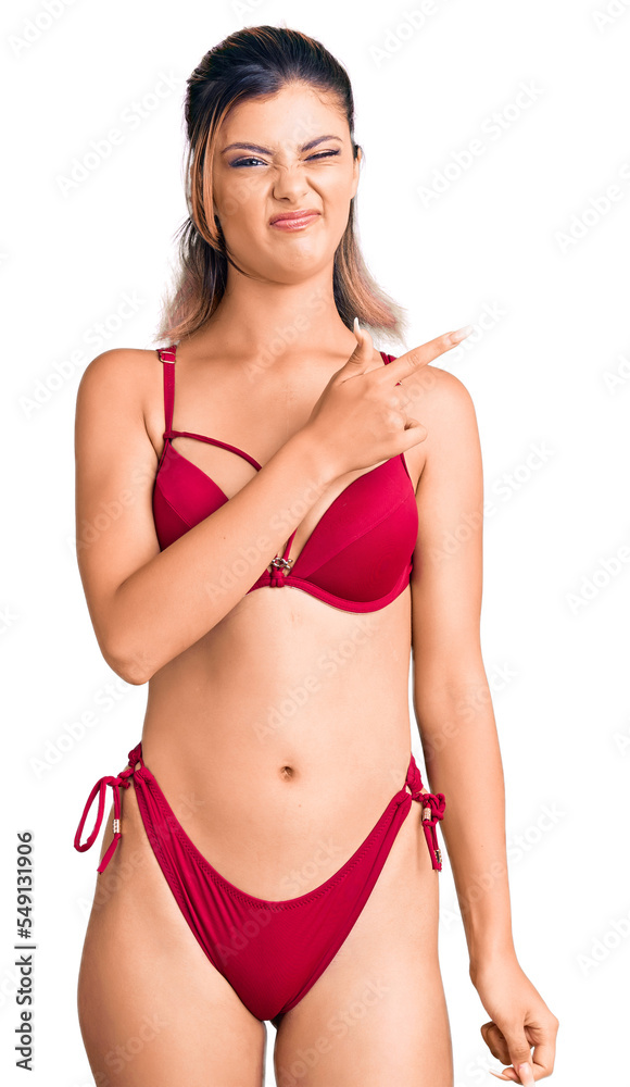 Fototapeta premium Young beautiful woman wearing bikini pointing aside worried and nervous with forefinger, concerned and surprised expression
