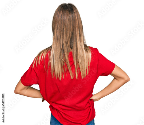 Teenager caucasian girl wearing casual red t shirt standing backwards looking away with arms on body