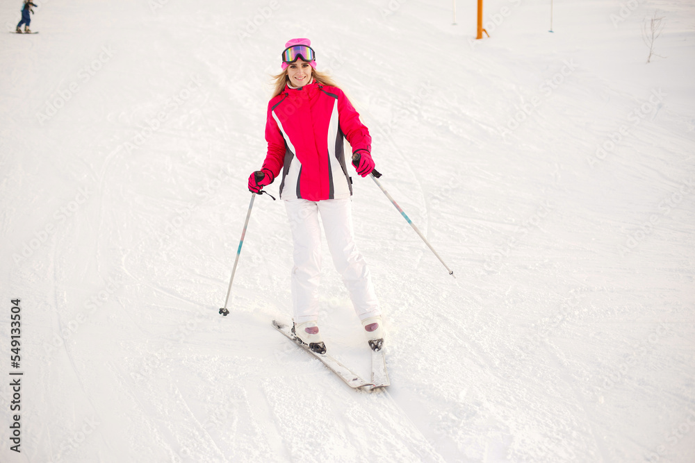 Girl skiing in mountains in a pink and white ski suit