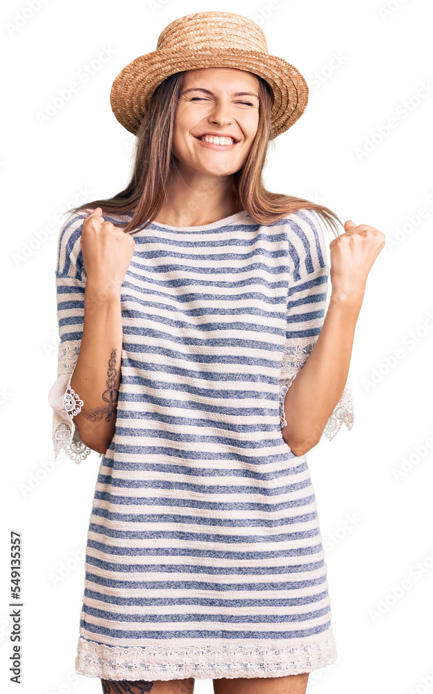 Beautiful caucasian woman wearing summer hat excited for success with arms raised and eyes closed celebrating victory smiling. winner concept. Beautiful caucasian woman wearing summer hat excited for success with arms raised and eyes closed celebrating victory smiling. winner concept.
