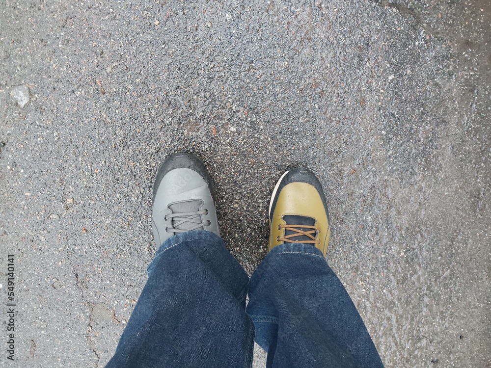 Legs of a man in winter sneakers of different colors Legs of a man in winter sneakers of different colors