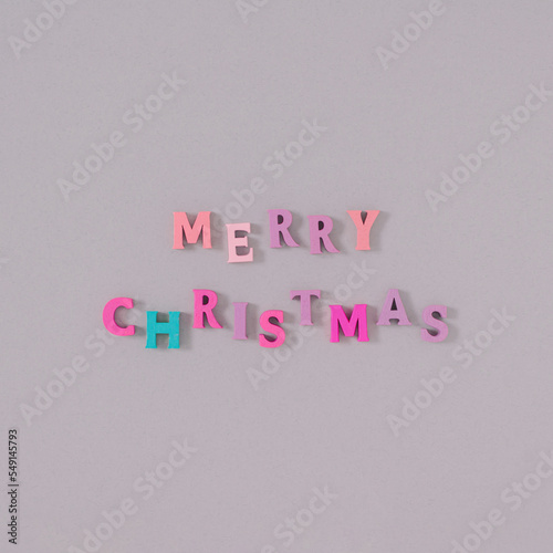 Creative MERRY CHRISTMAS Christmas tree decoration with light background made of colorful wooden letters. Minimal New Year party holiday concept. Flat lay.