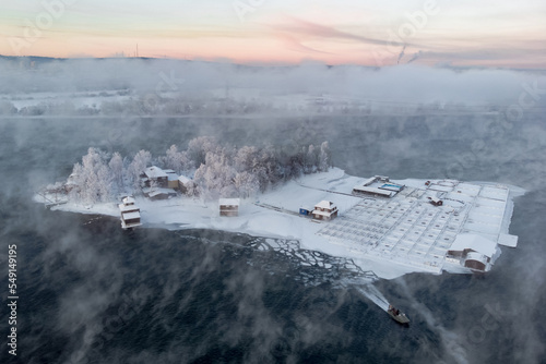 The boat sails away from the island on the Angara river during the winter fog photo