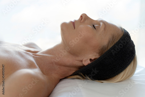 Side view of blonde mature woman laying at the couch after making facial procedure