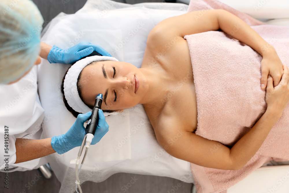Fototapeta premium Closeup portrait of female face with closed eyes getting microdermabrasion procedure
