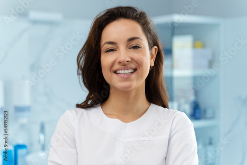 Portrait of cosmetologist in white lab coat looking at camera