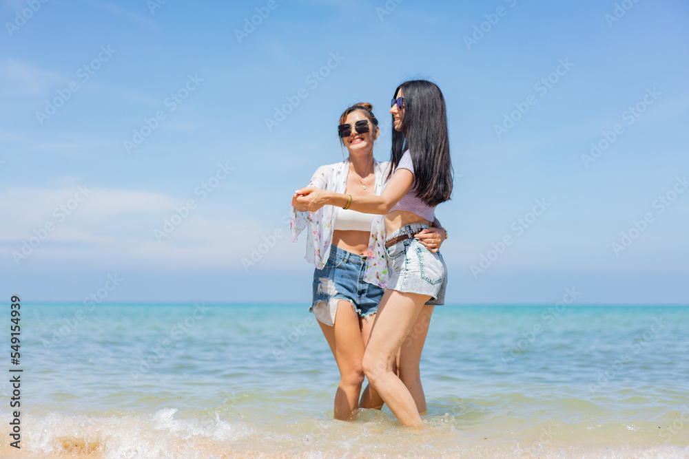 Two girlfriends hugging up and enjoying on the sea beach. A pair of girls in love cuddling on a tropical beach. romantic young lesbian couples in love and walking together on the beach.Concept of LGBT Two girlfriends hugging up and enjoying on the sea beach. A pair of girls in love cuddling on a tropical beach. romantic young lesbian couples in love and walking together on the beach.Concept of LGBT