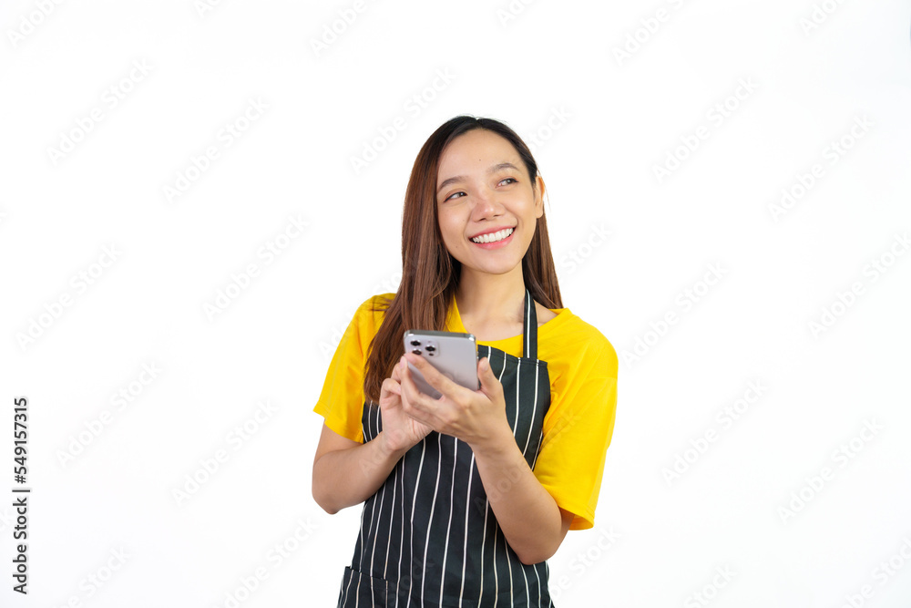 Texting on mobile to chat with customer, Portrait of confident asian woman barista and food owner shop with yellow t-shirt and black apron standing on white background. Texting on mobile to chat with customer, Portrait of confident asian woman barista and food owner shop with yellow t-shirt and black apron standing on white background.