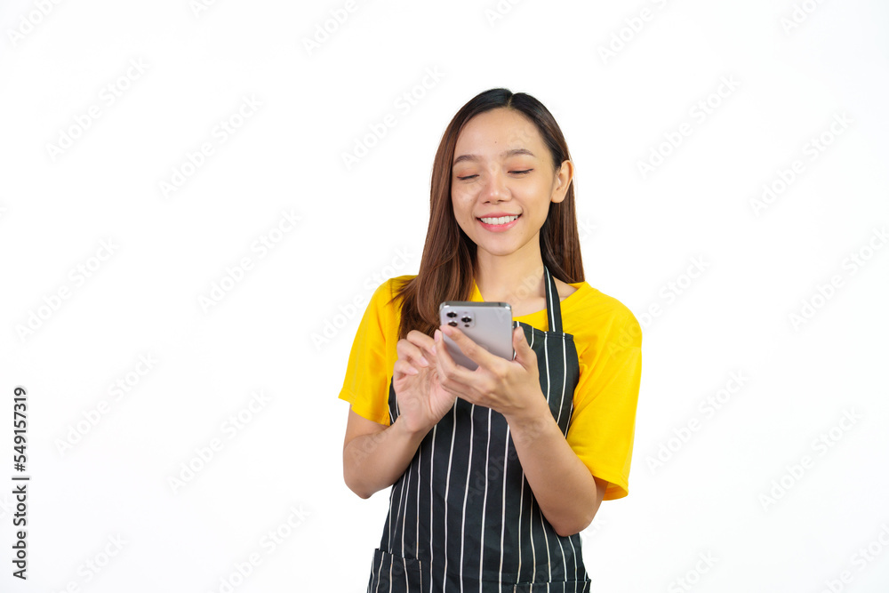 Texting on mobile to chat with customer, Portrait of confident asian woman barista and food owner shop with yellow t-shirt and black apron standing on white background. Texting on mobile to chat with customer, Portrait of confident asian woman barista and food owner shop with yellow t-shirt and black apron standing on white background.